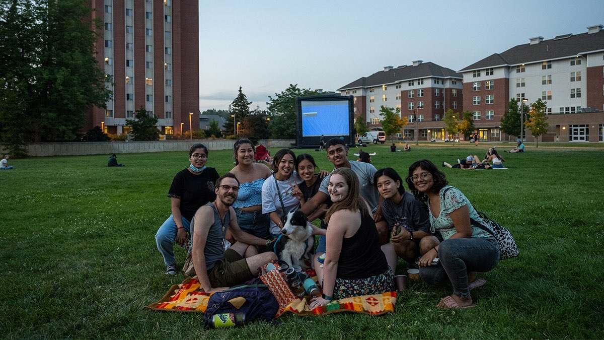 A group of students sitting on a blanket in the grass at the U of I campus