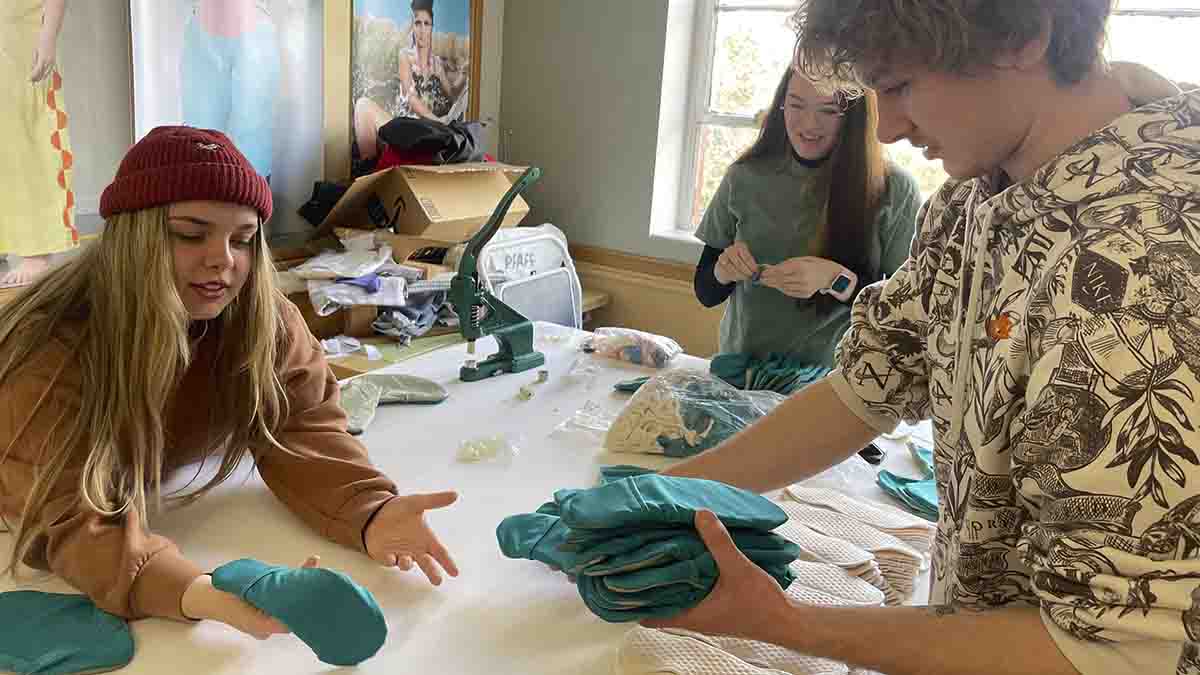 Three students working on making teal footwear.