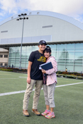A mother and son stand on the practice field of the P1FCU-Kibbie Activity Center.