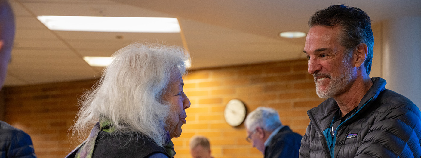 Tom Mueller smiles as he listens to a woman after his presentation.