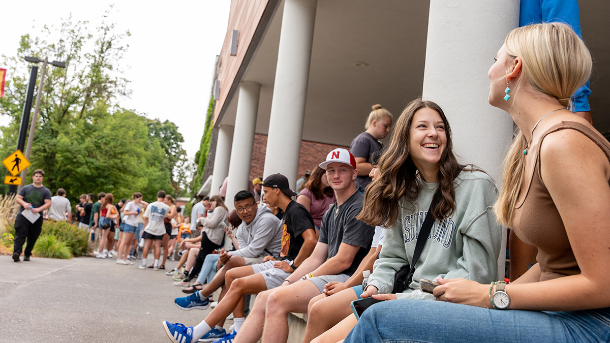 Group of students sitting outside a U of I building laughing