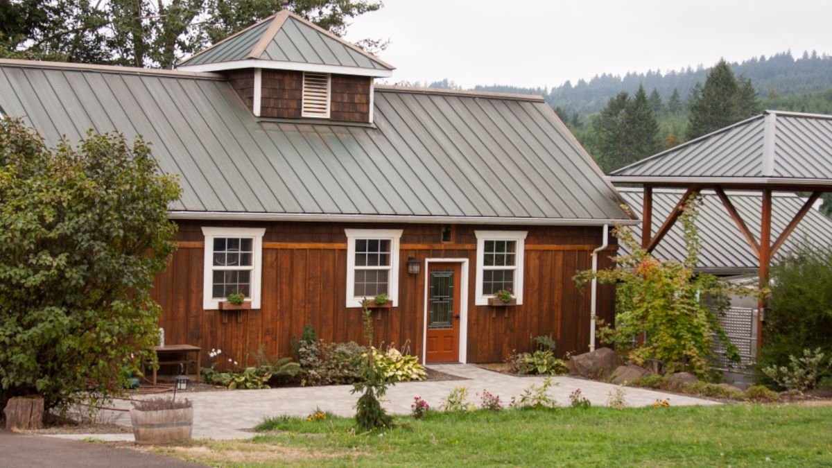 A barn-style wine cellar and patio with a luscious green lawn.