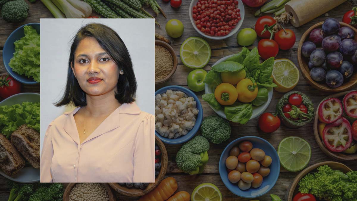 A portrait of a woman with a background of bowls of fruit and vegetables.