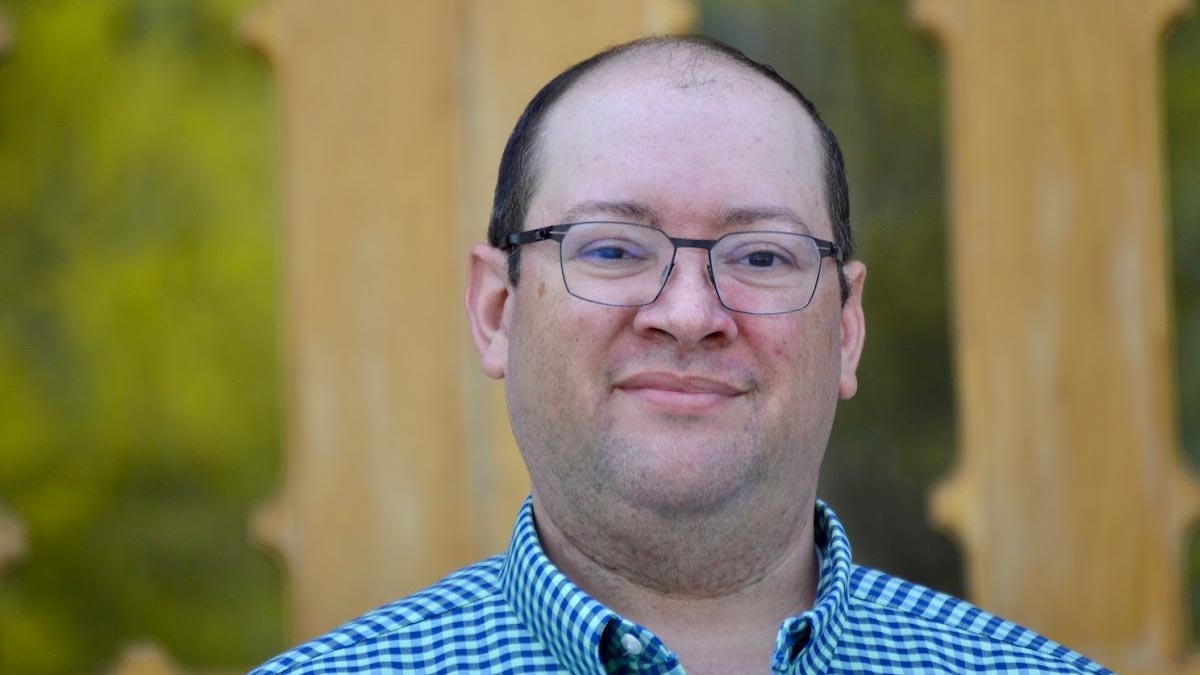 A portrait of a man in a blue checkered shirt.