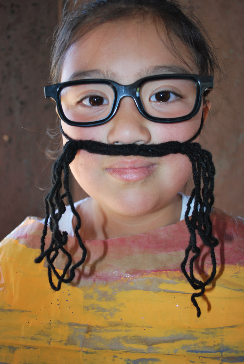 A child in costume with a yarn mustache.