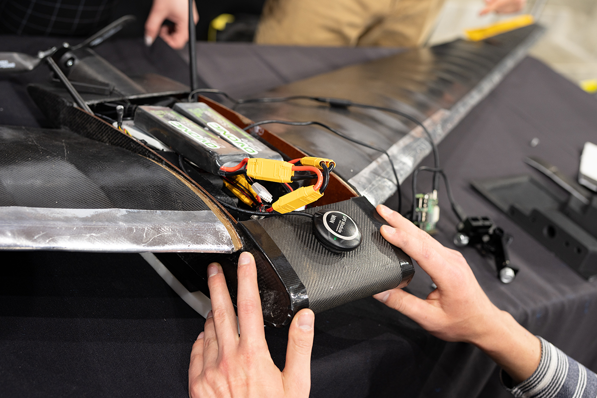 A student touches the nose of an unmanned arial vehicle prototype used for wildfire detection