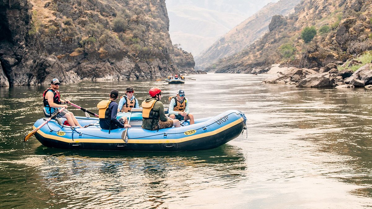 Five guys in a raft in the middle of a river