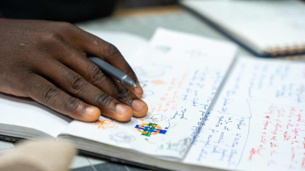 Closeup of hand holding pen on a notebook.