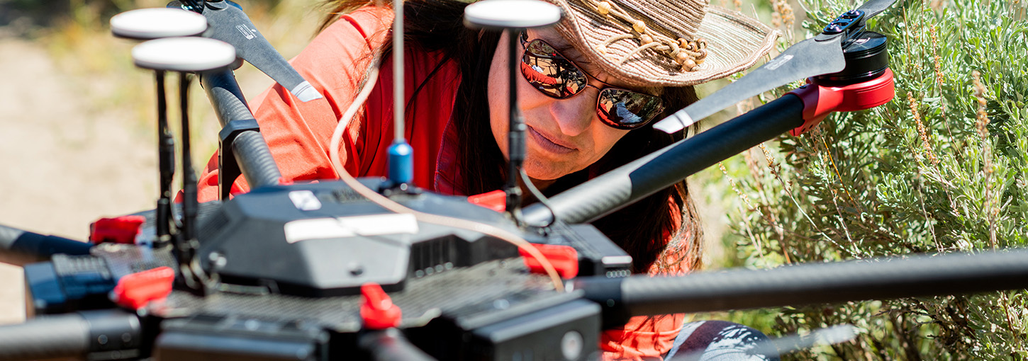 Person wearing western hat checks out a drone close up.