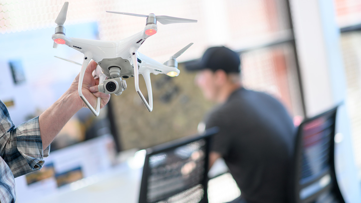 A person’s hand holds a drone in a lab.