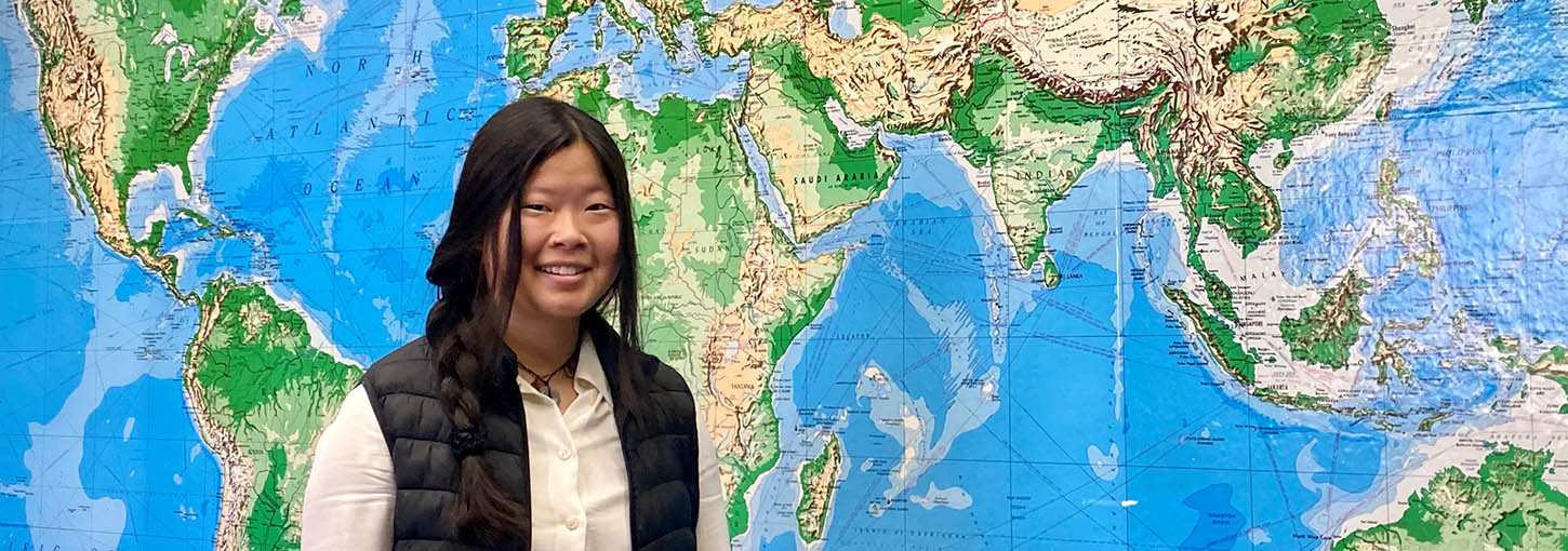 Woman standing in front of world map.