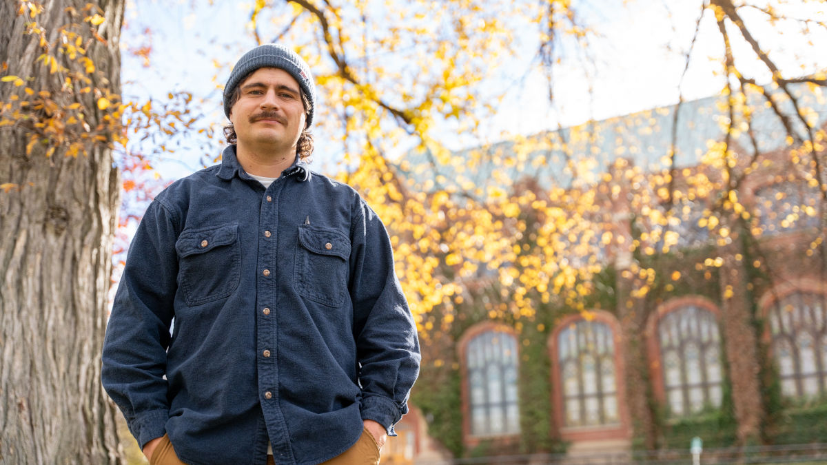 Man stands near a tree on campus.