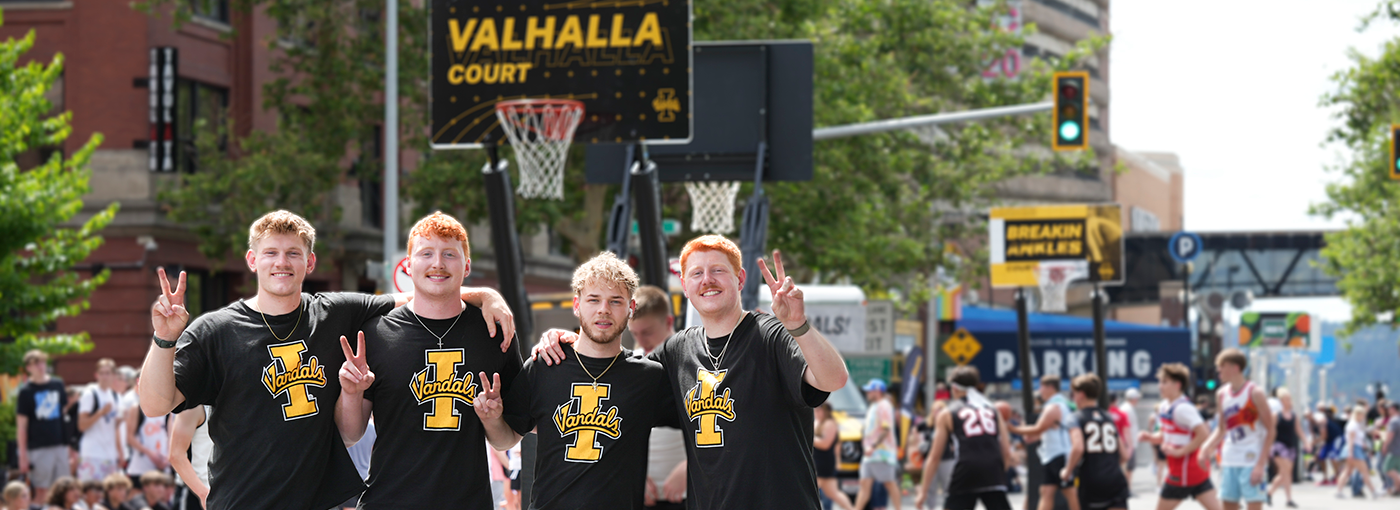 Four basketball players in black shirts in front of Vandal hoop.