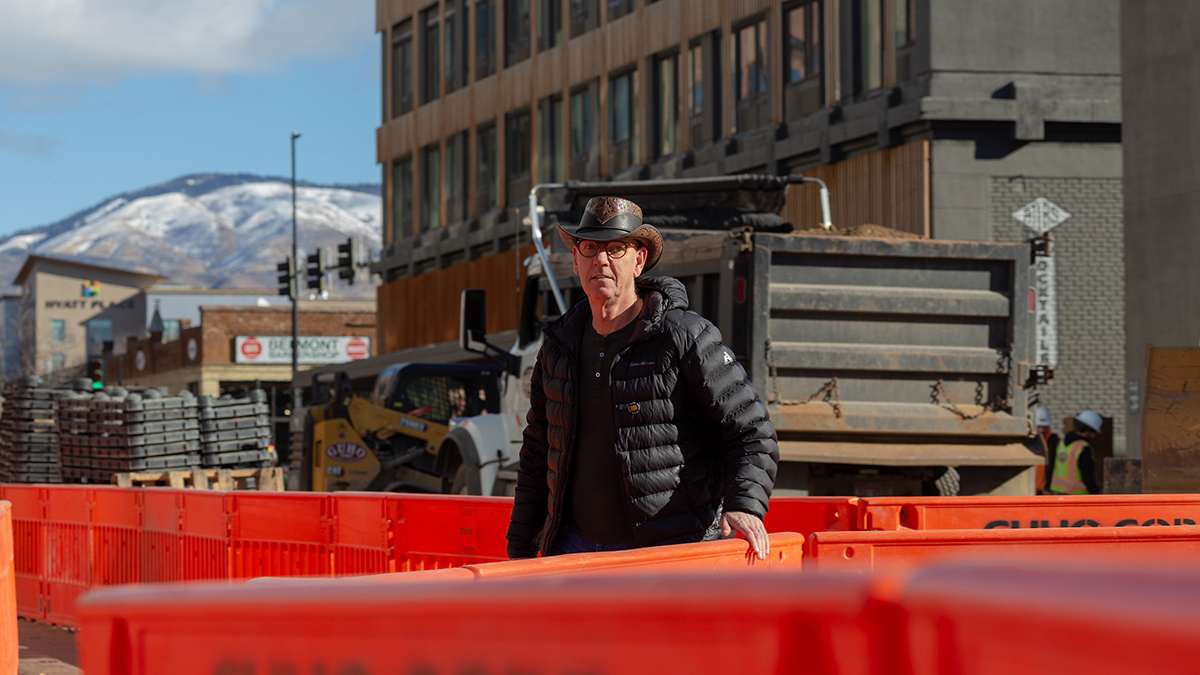 Jaap Vos walks through a construction site, brushing his hand along the safety-orange barriers. 