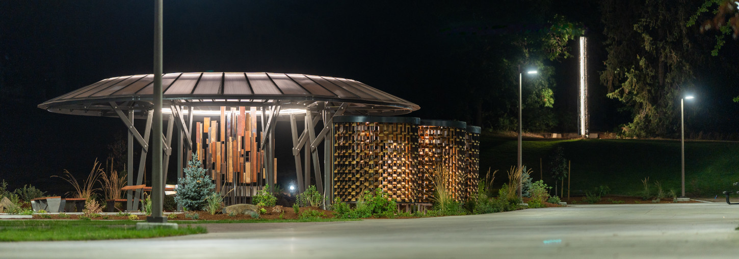 Memorial space at night with streetlights and beacon shining.