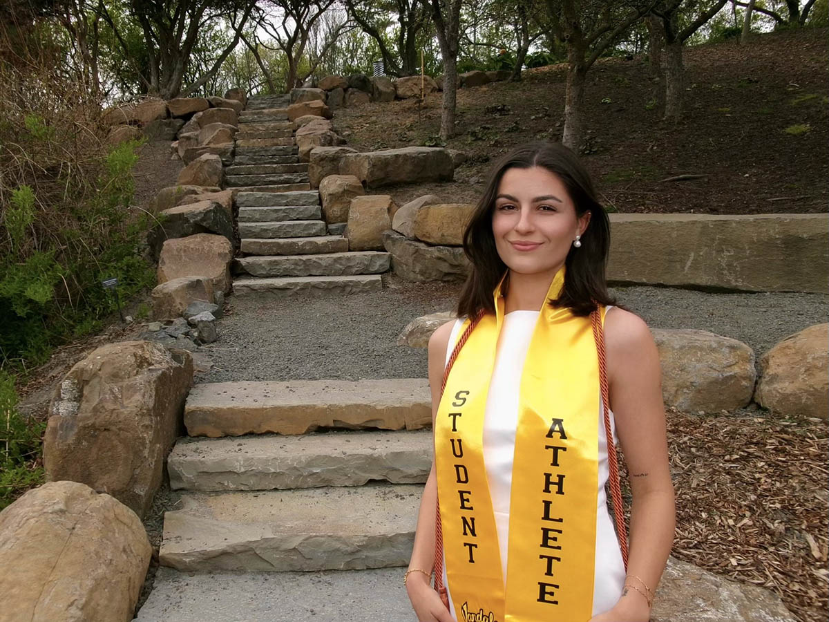 Woman in white dress and yellow banner standing by steps.