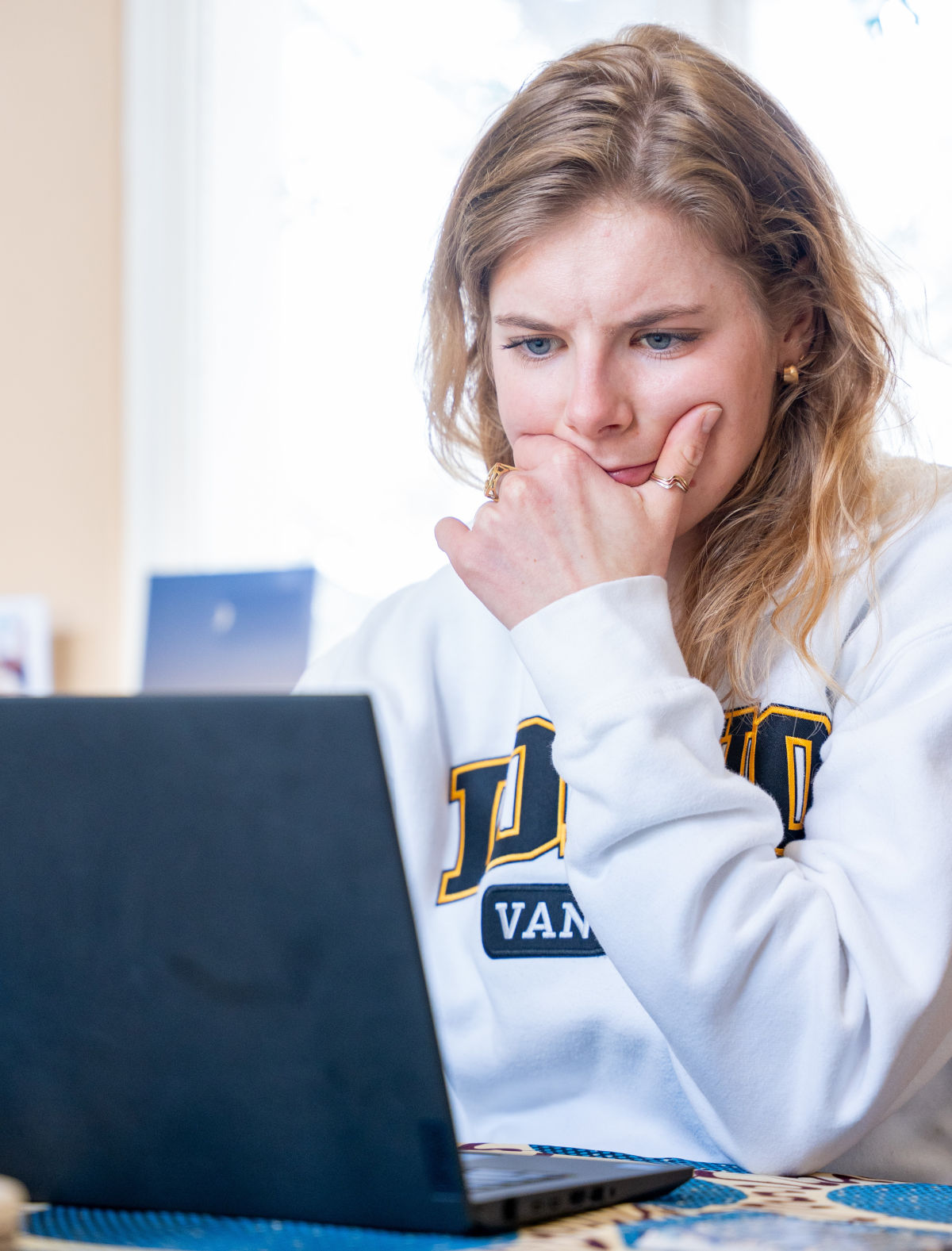 Woman in white U of I sweatshirt looking at laptop.