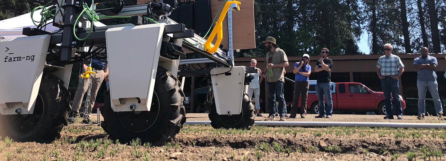 Wheeled machine in a seedling bed with people watching