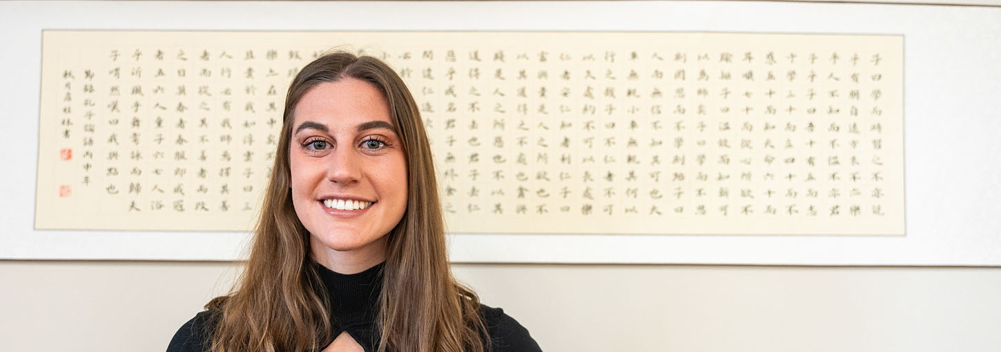 Woman stands in front of art with Japanese characters.