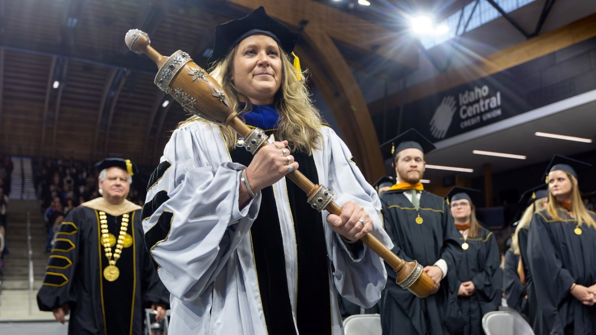 Faculty, Erin Chapman carrying the ceremonial mace at Commencement.